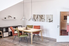A dining area with a wooden table and chairs, pendant lighting, and artwork on the wall. - Apartment in Plau am See with swimming pool (Plau am See)