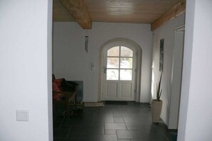 A hallway with a tiled floor, a wooden ceiling, a white door with glass panels, and a potted plant. - Holiday home with 2 bedrooms (Risum-Lindholm)
