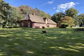 A traditional brick house with a thatched roof, surrounded by a well-maintained lawn and trees. - Holiday home with 2 bedrooms (Risum-Lindholm)