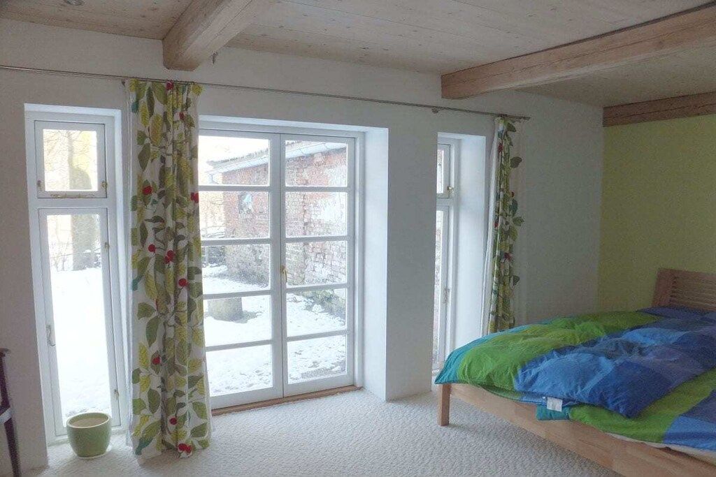 A room with a bed, a window, and a door.