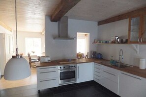 A kitchen with white cabinets, a built-in oven, a large pendant light, and a wooden countertop. - Holiday home with 2 bedrooms (Risum-Lindholm)