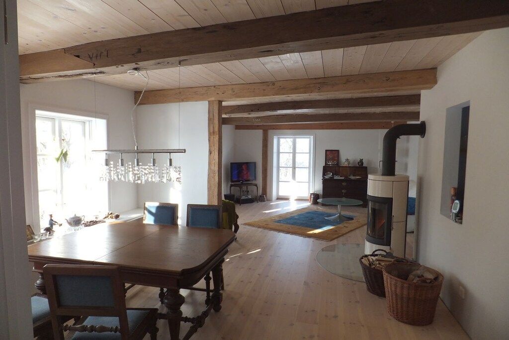 Ein geräumiger Raum mit einem Holzessttisch, Stühlen, einem Kamin und einem Fernseher.