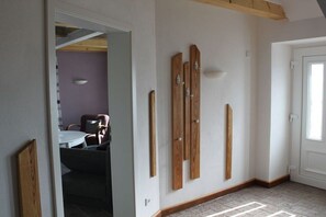 A room with a white door, a dining area with a table and chairs, and wooden wall decorations. - House Uhlenstraat - Apartment Theo (Esgrus)