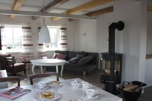 A cozy living room with a fireplace, a round dining table with tea cups and plates, and a sofa with cushions. - House Uhlenstraat - Apartment Theo (Esgrus)
