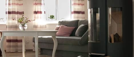 A living room with a sofa, a table, and a black wood-burning stove.