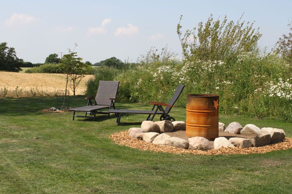 Ein Garten mit zwei Liegestühlen, einer Feuerstelle und einer Rasenfläche.