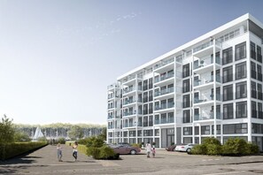 Un edifici residencial de diverses plantes amb balcons i una zona d'aparcament.