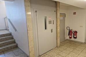 A stairwell with a fire door, fire extinguishers, and a sign on the wall. - South Beach happiness (Burgtiefe-Südstrand)