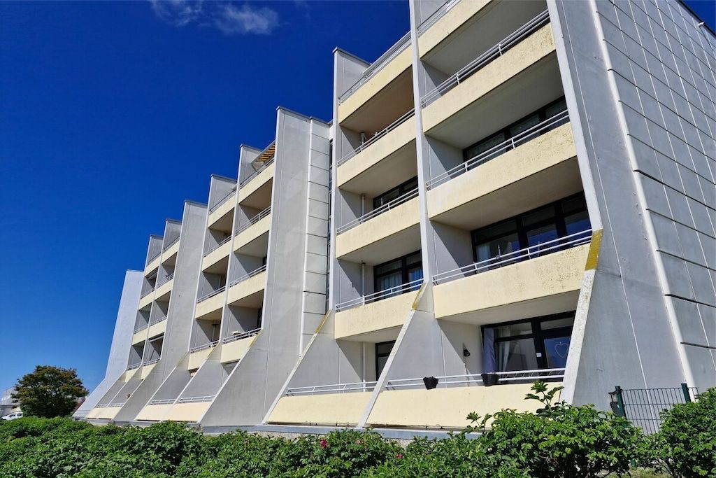 A multi-story building with balconies, a flat roof, and a clear sky.