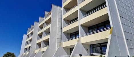 A multi-story building with balconies, a flat roof, and a clear sky.