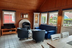 Ein gemütliches Wohnzimmer mit Kamin, Fernseher und einer Couch.