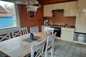 A compact kitchen with white cabinets, a wooden table, and a blue vase. - Holiday home with 3 bedrooms (Boltenhagen)