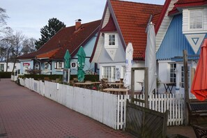 A row of traditional buildings with a white picket fence, outdoor seating, and a red-tiled roof. - Holiday home with 3 bedrooms (Boltenhagen)