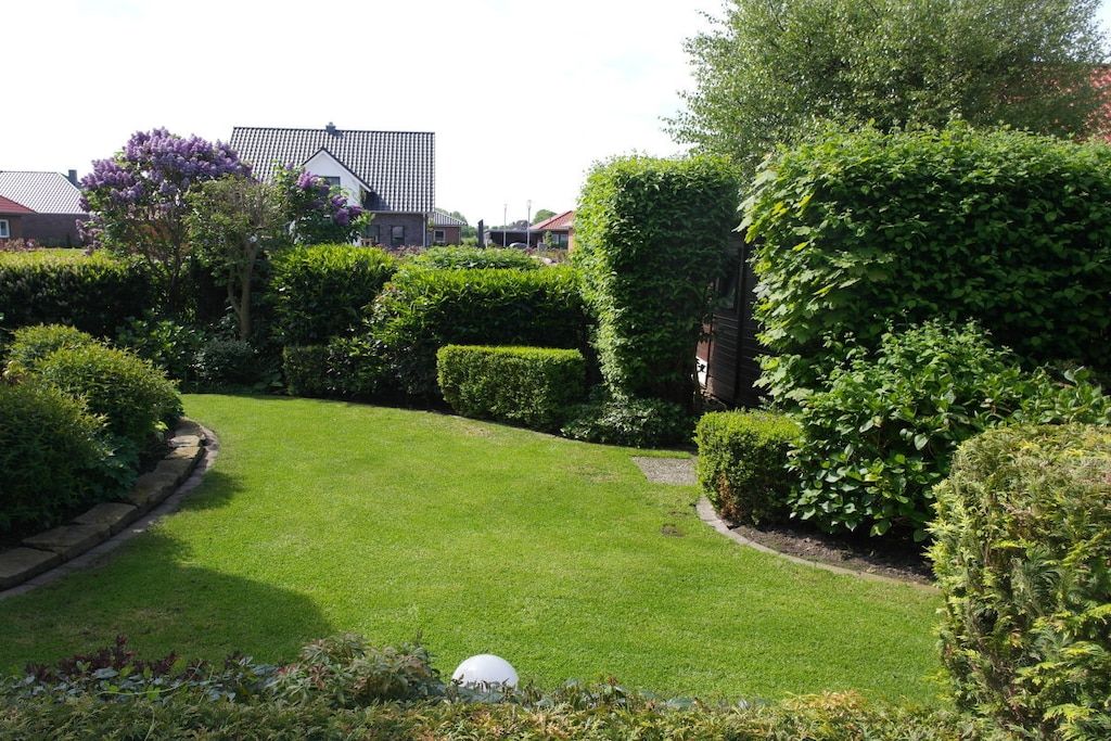 A well-maintained garden with neatly trimmed hedges and a lawn.