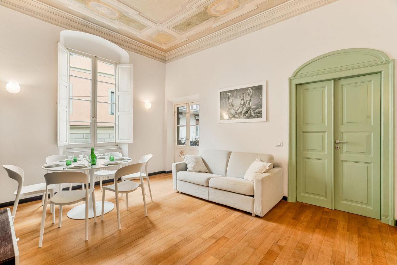 Une pièce comprenant une table à manger, des chaises, un canapé et une porte verte.