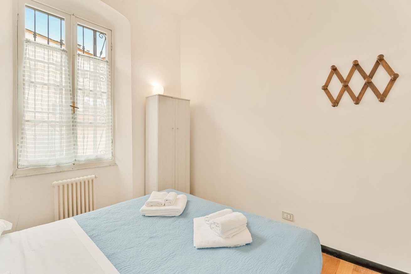 Un dormitorio con cama, radiador, ventana con cortinas, armario y una decoración en la pared.