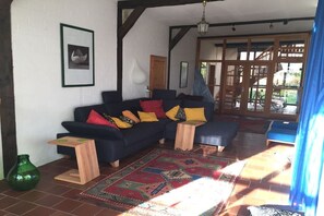 Ein Wohnzimmer mit einem dunkelblauen Sofa, mehreren Kissen, einem gemusterten Teppich und einem Holztisch.