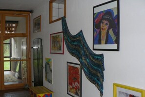 Ein Zimmer mit einer Holztür, einem Spiegel und verschiedenen gerahmten Kunstwerken an der Wand.