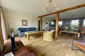 A living room with a sofa, a coffee table, a wicker chair, and a television. - Holiday home in Tramm with swimming pool (Tramm)