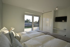 A bedroom with two beds, a large window, a TV, and a wardrobe. - Holiday apartment with 2 bedrooms (Kronsgaard)