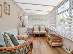 A cozy room with wicker furniture, a sofa, a small table, and a radiator. - Branwen (Holywell)