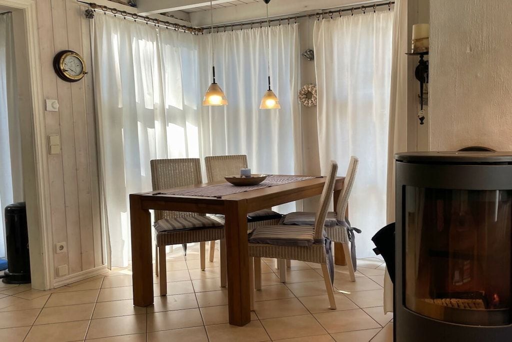 A dining area with a wooden table and chairs, a fireplace, and a curtain-covered window.