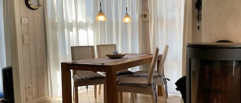 A dining area with a wooden table and chairs, a fireplace, and a curtain-covered window.