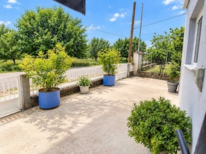 Ein Balkon mit Blumentöpfen, einem weißen Zaun und blauem Himmel.