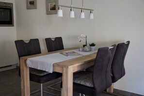 Ein Essbereich mit einem Holztisch, vier Stühlen und einer Hängelampe.
