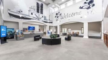 Un hall d’entrée spacieux, agrémenté d’une pancarte « Bienvenue », d’un comptoir d’accueil, de coins salon et d’un grand écran numérique.