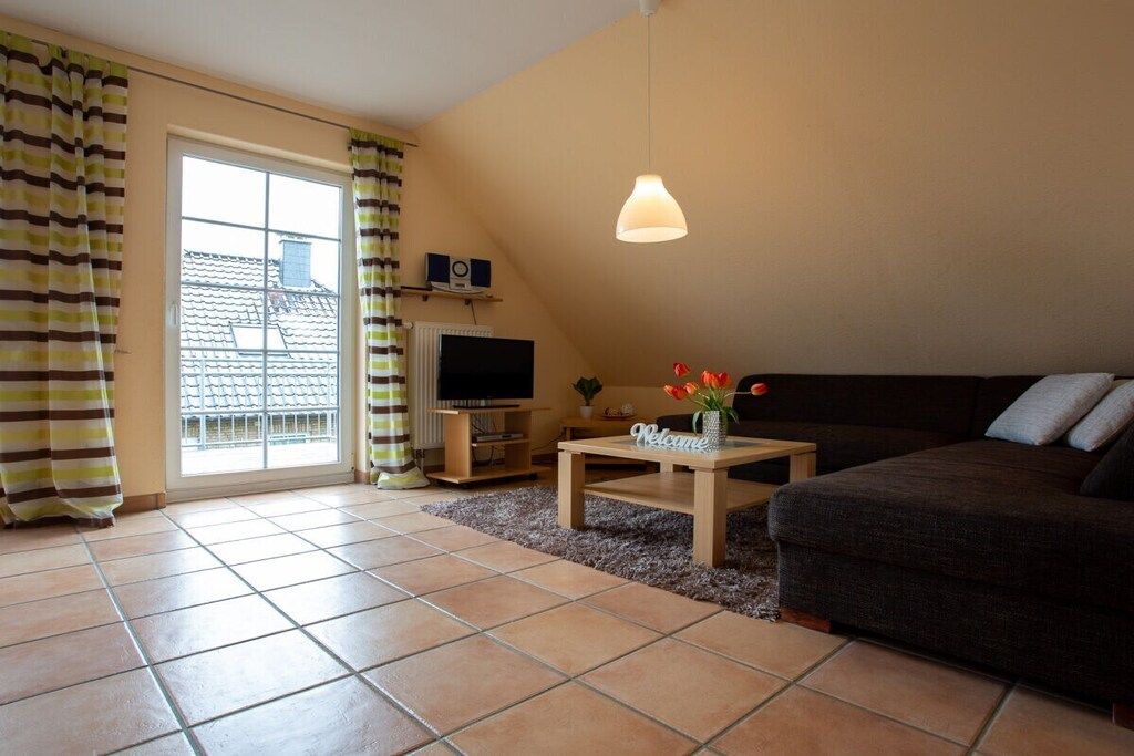 A living room with a sofa, a coffee table, a TV, and a window with curtains.