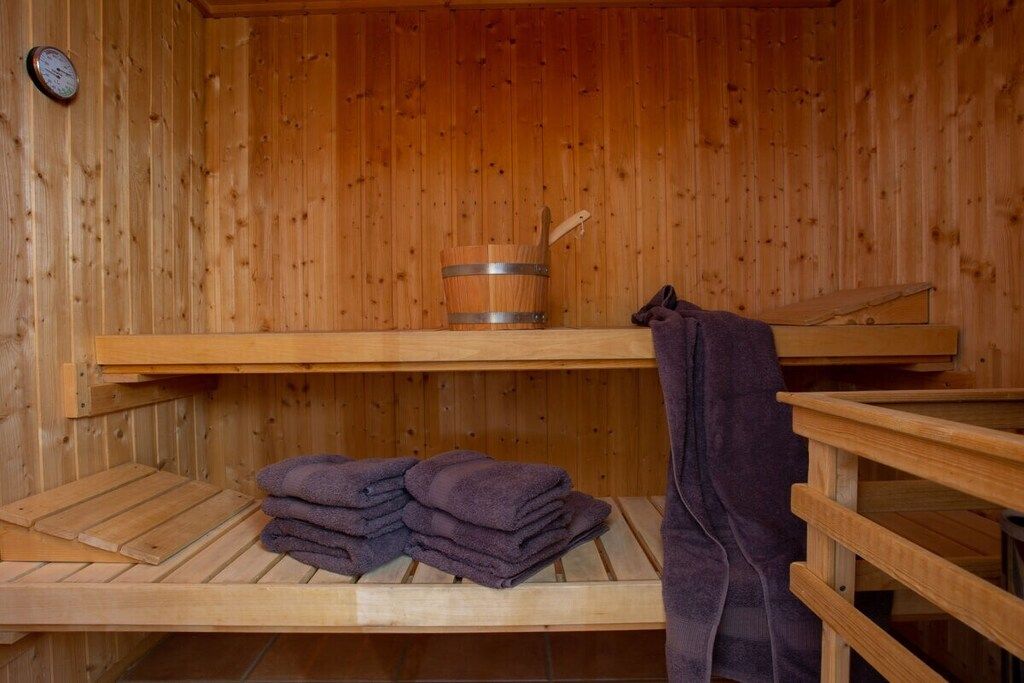 Un sauna en bois avec un banc en bois, une pile de serviettes et un seau en bois.