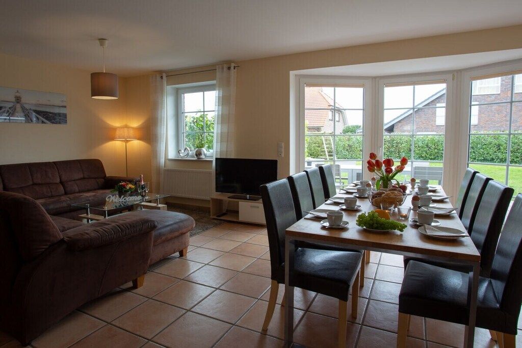 Un coin repas avec une table dressée pour quatre personnes, un canapé, un téléviseur et une lampe.