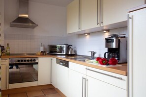 A modern kitchen with white cabinets, stainless steel appliances, and a wooden countertop. - Holiday home with 4 bedrooms (Ostseebad Schönhagen)