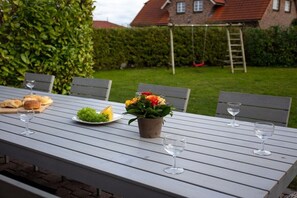 An outdoor dining table with chairs, a flower arrangement, and food items. - Holiday home with 4 bedrooms (Ostseebad Schönhagen)