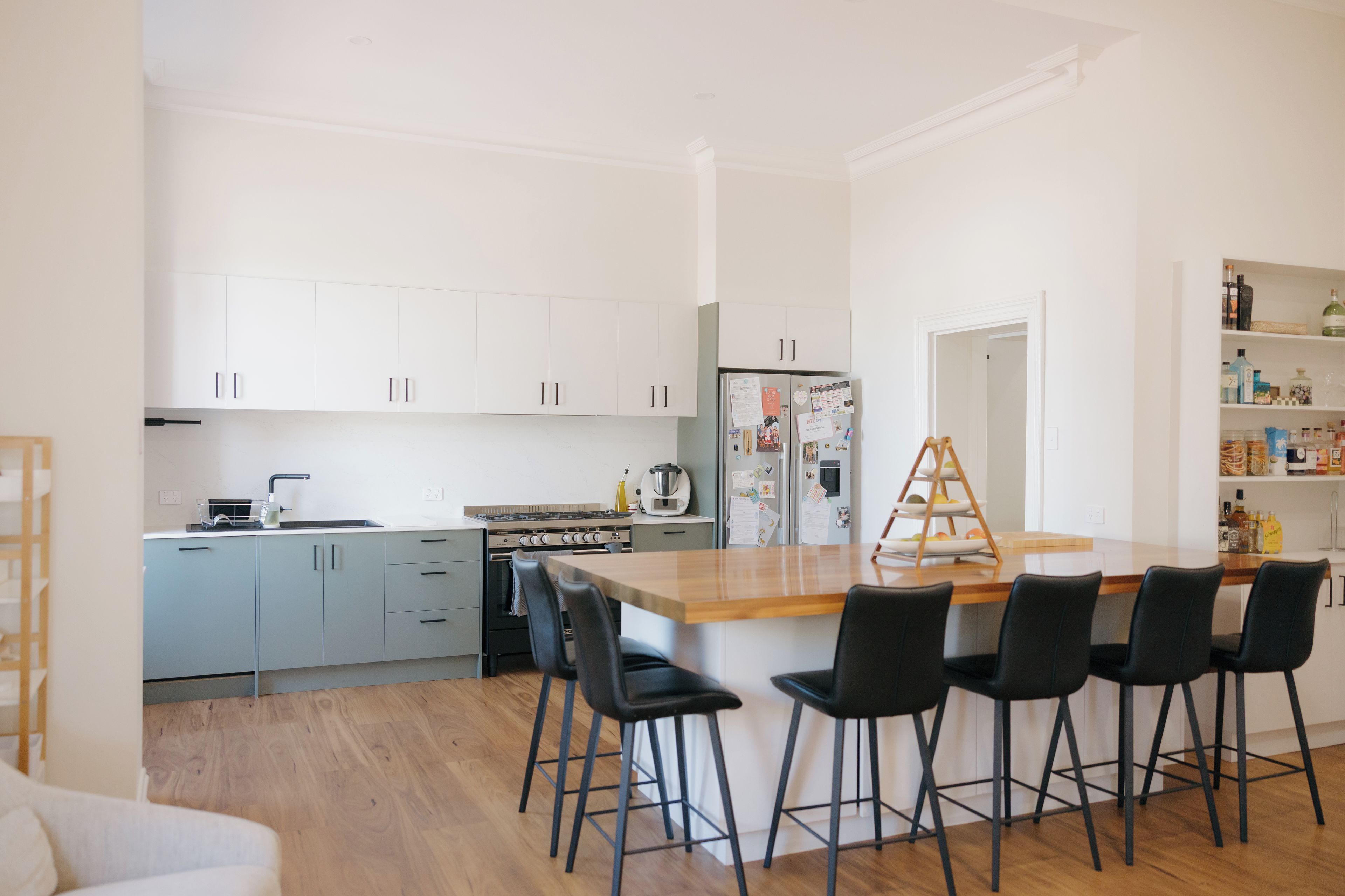 A modern kitchen with a central island, bar stools, and a refrigerator with magnets.