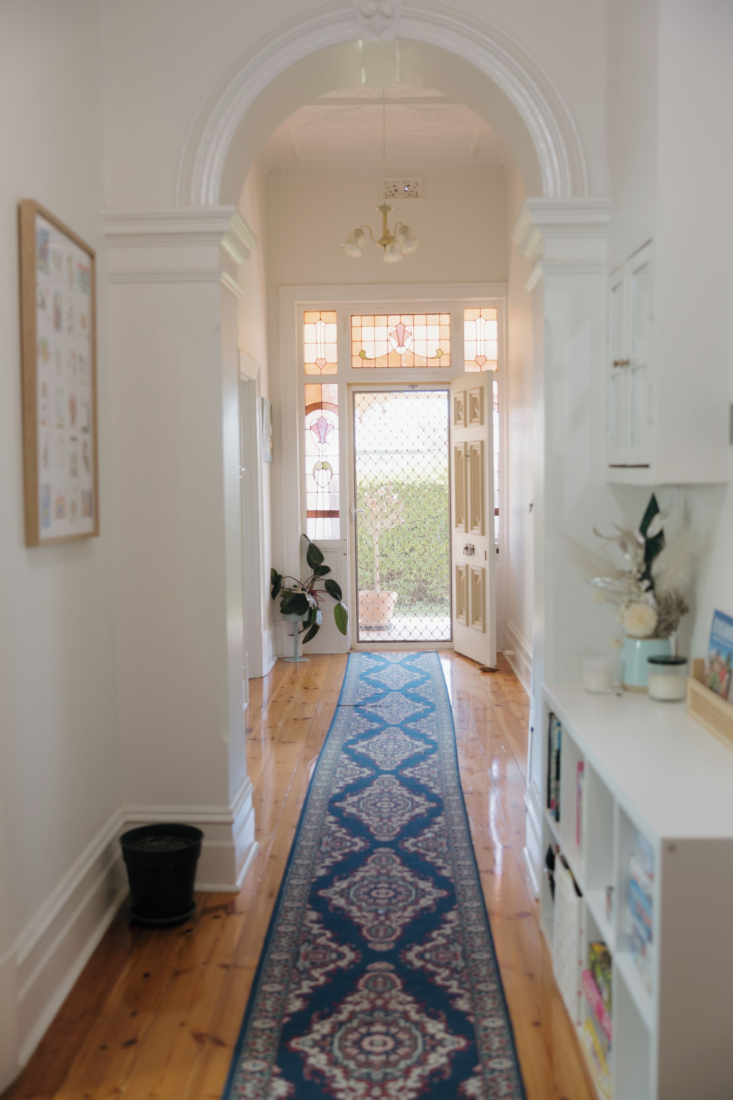 A hallway with a patterned carpet, white walls, and a door leading to an outdoor area.