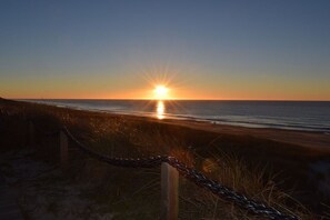A sunset over the ocean with a chain-link fence in the foreground. - No. 03 in the Atlantic House (Wenningstedt)
