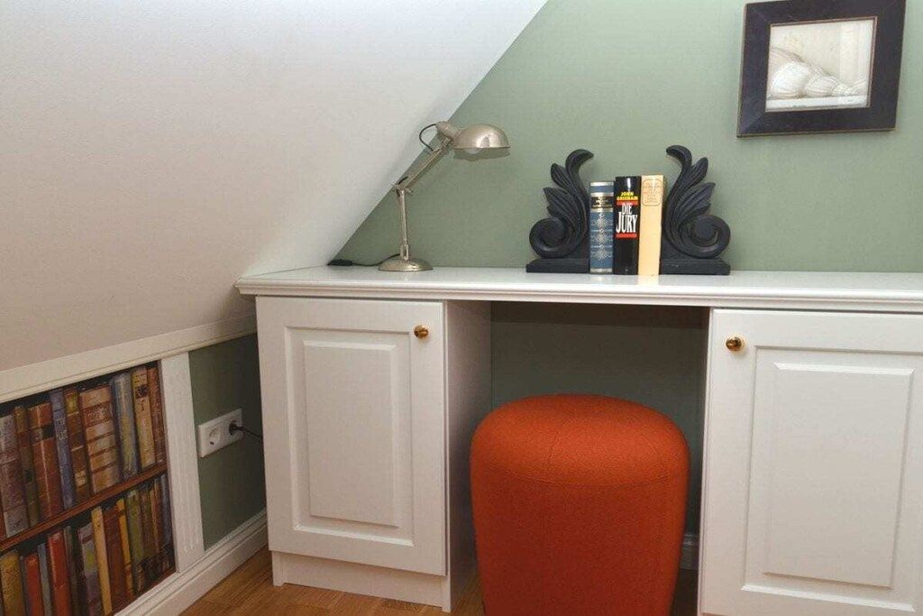Un espace de travail comprenant un bureau, des livres, une lampe et une chaise.