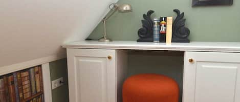 A study area with a desk, books, a lamp, and a chair.