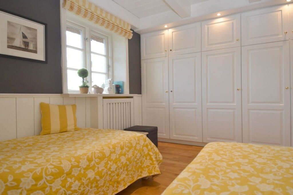 Une chambre avec deux lits, une fenêtre avec des rideaux, un radiateur et une armoire.