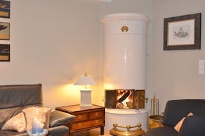 A living room with a fireplace, a sofa, a lamp, and a framed picture on the wall. - Holiday home in Nieblum with swimming pool (Nieblum)