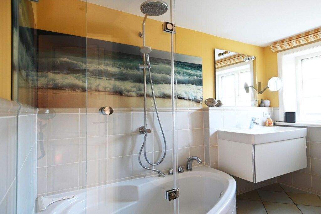 Ein Badezimmer mit Badewanne, Dusche, Waschbecken und Spiegel.