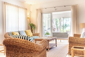 A room with wicker furniture, a sliding glass door leading to an outdoor area, and a potted plant. - Oceanfront Villa - East Coast, Private beach & Pool (Quatre Cocos)