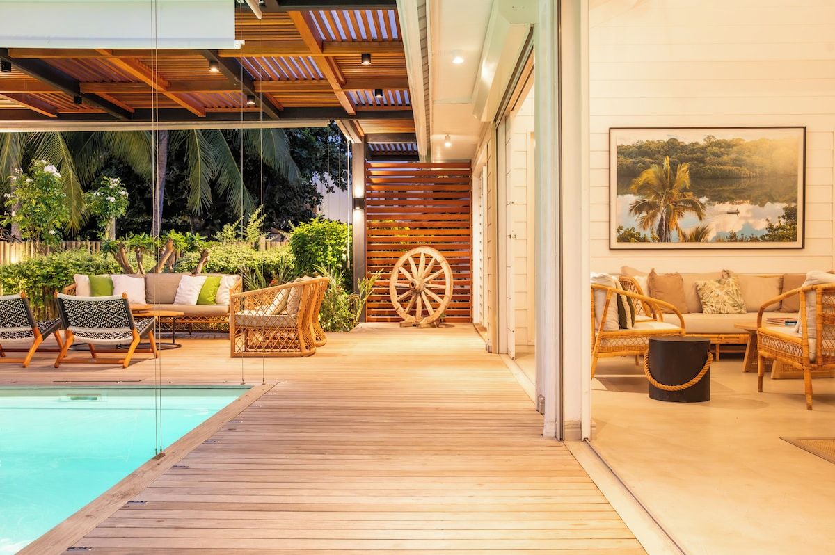 Ein Poolbereich mit Holzterrasse, Korbmöbeln und einer großen Holzradkonstruktion.