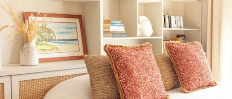 A bedroom with a bed, a bookshelf with books and decorative items, and a painting on the wall.