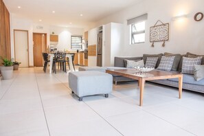 Un salon moderne avec un canapé, un pouf et une table basse.
