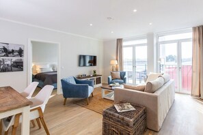 Een moderne woonkamer met een bank, stoelen, een salontafel en een televisie.