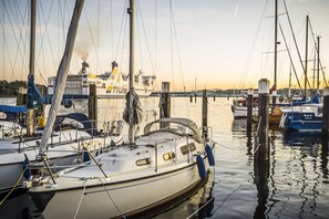 A marina with several sailboats docked, a large ship in the background, and calm water reflecting the boats. - Holiday apartment with 1 bedroom (Lübeck Travemünde)
