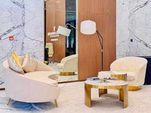 A modern interior with a curved sofa, a round gold table, and a tall floor lamp. - Trillionaire 1BR Trendy Timeless Tempting (Dubai)